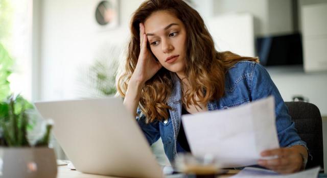 Todo lo que necesitas saber para aplazar tus deudas con Hacienda. Imagen de una mujer con cara de agobio mirando unos papeles