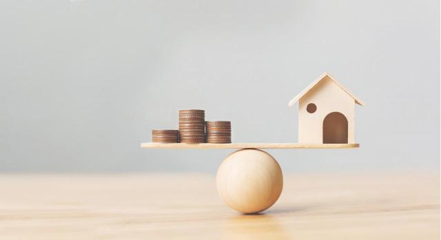 IIVTNU: Valores del adquisición y transmisión en el caso de viviendas transmitidas por las empresas dedicadas a la construcción y promoción inmobiliaria IIVTNU: Valores del adquisición y transmisión en el caso de viviendas transmitidas por las empresas dedicadas a la construcción y promoción inmobiliaria. Imagen de casa de madera y monedas de dinero apiladas en escala